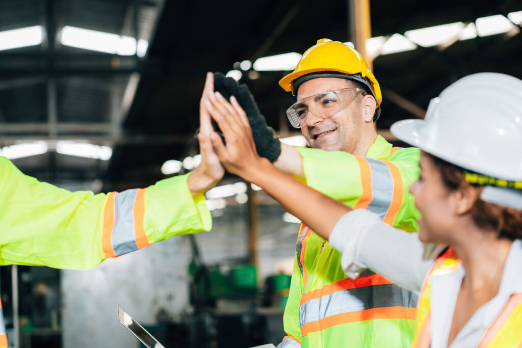 Employees in safety gear high-fiving