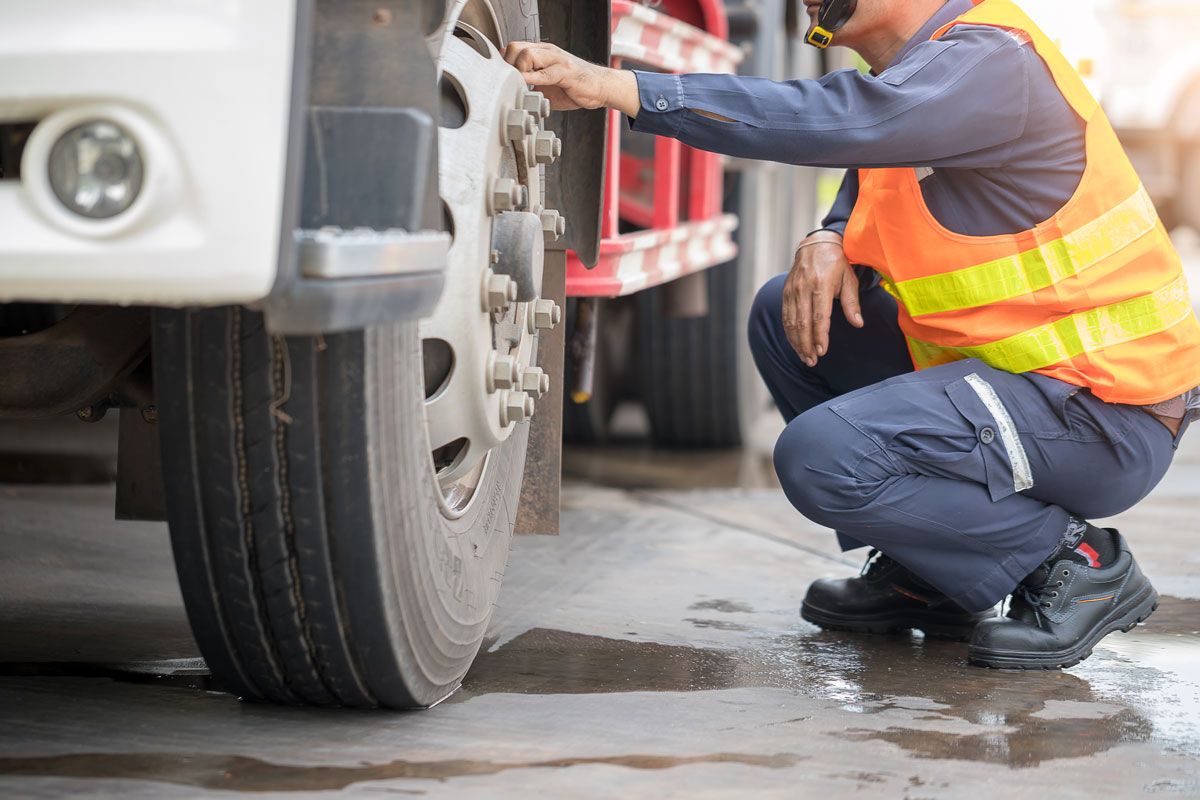 Person in safety vest inspecting large tire on a truck